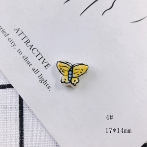 Macro detail of yellow ceramic butterfly bead with hand-painted patterns measuring 17x14mm