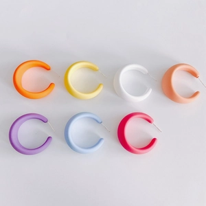Detailed macro view of seven pairs of colorful matte acrylic C-shaped hoop earrings