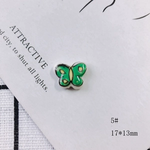 Detail of 17x13mm green and yellow butterfly ceramic bead with glossy finish and black outlines