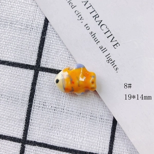 Macro view of a 19x14mm handmade orange ceramic fish bead for DIY jewelry making