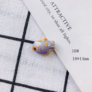 Macro shot of 18x14mm handmade lavender ceramic fish bead with orange accents
