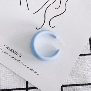 Detail of light blue matte C-shaped hoop earring on a stylish decorative card