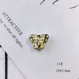 Macro view of 18x14mm yellow butterfly ceramic bead with hand-painted wing details