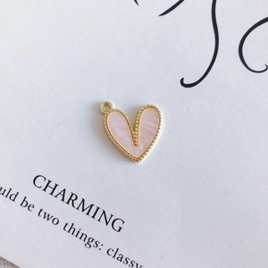 Dettaglio del ciondolo a cuore in conchiglia rosa con cornice dorata per gioielli DIY