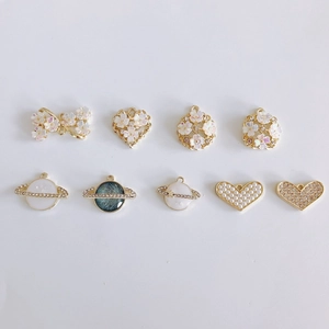 Detail view of DIY alloy gold pendants with bow, planet, flower and pearl inlay designs