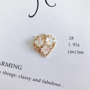 Macro shot of 19x13mm heart charm with golden metal base, white flowers and rhinestones