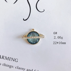 Macro shot of 22x16mm gold Saturn pendant with blue inlay and rhinestone details