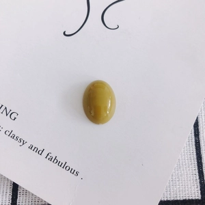 Macro detail of a polished oval green-yellow resin gemstone for DIY jewelry making