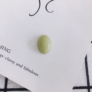 Close-up of light green oval resin cabochon with smooth polished finish for DIY crafts