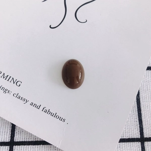 Macro view of a polished mocha oval resin gemstone for DIY accessories on card