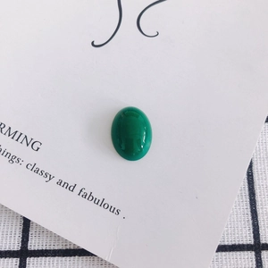 Macro shot of an oval green malachite resin cabochon with smooth glossy finish for DIY crafts