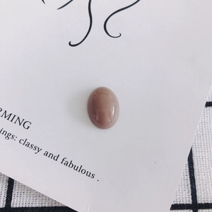 Close-up of smooth oval mocha resin bead on artistic paper over a checkered cloth