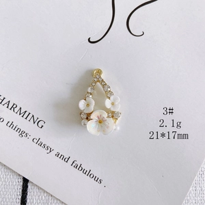 Detailed macro view of 21x17mm gold floral pendant with pearl and shell flower accents