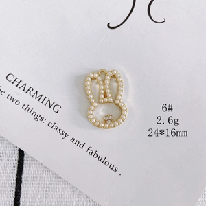 Macro detail of a 24x16mm golden rabbit pendant with pearls and zircon stones