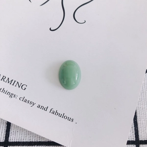 Macro shot of oval green resin cabochon with smooth glossy finish for DIY jewelry crafts