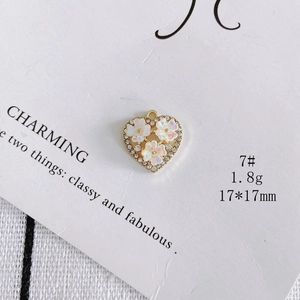 Macro detail of heart-shaped pendant with floral shell inlay and rhinestones, 17x17mm size