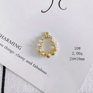 Detailed view of pear-shaped golden pendant with white pearls and sparkling crystals