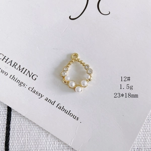 Detailed view of pear-shaped gold pendant with pearls and rhinestones, 23x18mm size