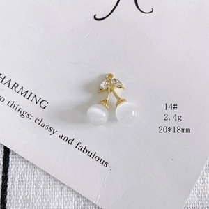 Detail of gold cherry pendant charm with white cat eye stones and sparkling rhinestones