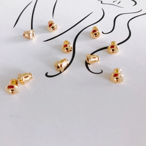 Minimalist gold earring backs displayed on an artistic female profile line drawing