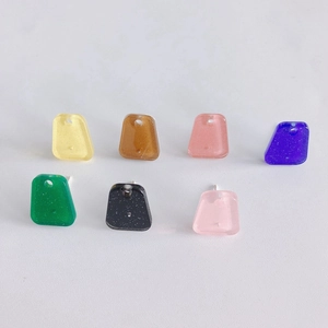 Macro shot of colorful trapezoid resin earring charms with subtle glitter and silver pins