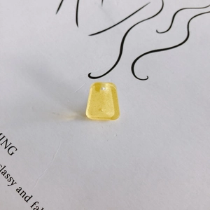 Macro detail of trapezoid yellow acrylic pendant with gold glitter and pre-drilled hole