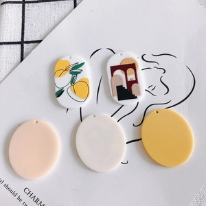 Flat lay of acrylic DIY jewelry pendants with cartoon rabbit and geometric patterns
