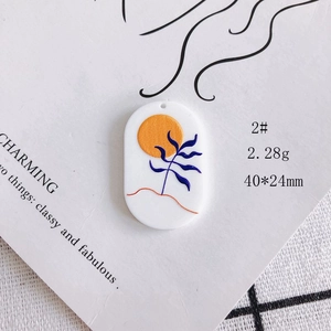 Detail of an oval acrylic pendant with a sun and blue leaf motif for DIY jewelry