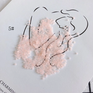 Macro view of 2mm pale pink glass seed beads for DIY jewelry making on white card