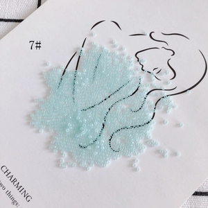 Macro view of 2mm light blue glass seed beads on a minimalist line art display card