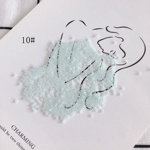 Macro detail of 2mm light blue glass seed beads arranged on a creative display card