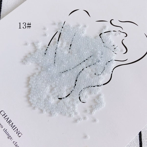 Macro shot of 2mm light blue glass seed beads scattered on a card for DIY jewelry making