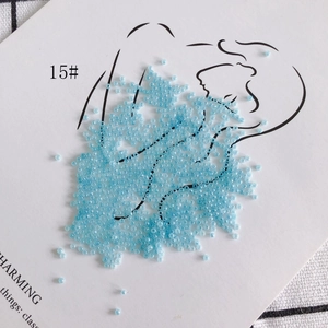 Macro shot of 2mm light blue glass seed beads on artistic white decorative card