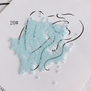 Macro detail of 2mm light blue glass seed beads with glossy finish on artistic canvas