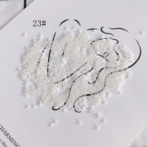 Close-up of 2mm cream-colored glass seed beads for DIY jewelry on a minimal card