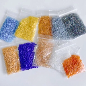 Macro detail of 2mm assorted glass seed beads organized in small plastic storage bags