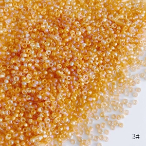Macro shot of 2mm bright orange AB glass seed beads with glossy finish for DIY jewelry