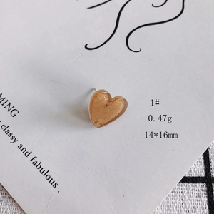 Vista ravvicinata degli orecchini a cuore in acrilico ambra con glitter e perno argento