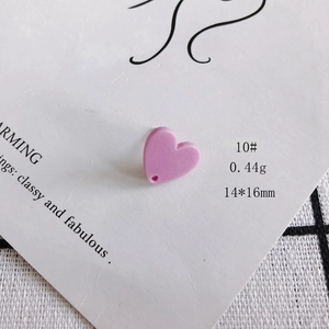 Dettaglio macro di un ciondolo a cuore in acrilico rosa 14x16mm con foro per gioielli DIY