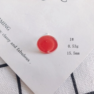 Detail of red circular acrylic earring with subtle glitter on decorative card