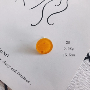 Detail of 15.5mm translucent orange acrylic round earring stud with fine glitter flakes