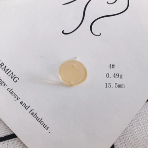 Detail of a 15.5mm light yellow acrylic round stud earring on a white display card