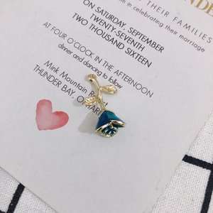 Detail of blue enamel rose pendant with gold stem on a vintage letter background