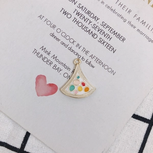 Close-up of golden fan-shaped alloy pendant with colorful enamel dots and jump ring