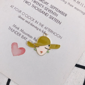 Macro shot of retro enamel charms featuring a woman in a green hat with rhinestone details