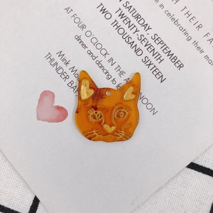 Vue détaillée du pendentif chat en résine marbrée orange avec des détails dorés gaufrés