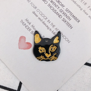 Vue détaillée d'un pendentif chat noir en résine avec détails dorés sur une carte blanche