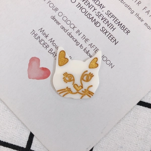Détail d'un pendentif chat en acrylique blanc avec oreilles à paillettes dorées