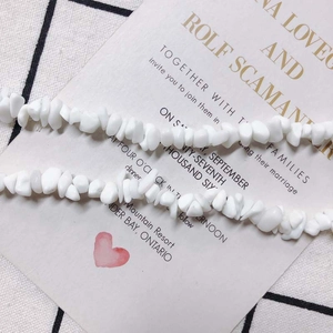 Detailansicht von unregelmäßigen weißen Steinchenperlen auf einer Hochzeitseinladung