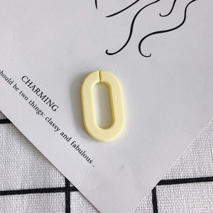 Mattgelbe ovale Acryl-Glieder für DIY-Schmuck auf weißer Karte mit Karostoff